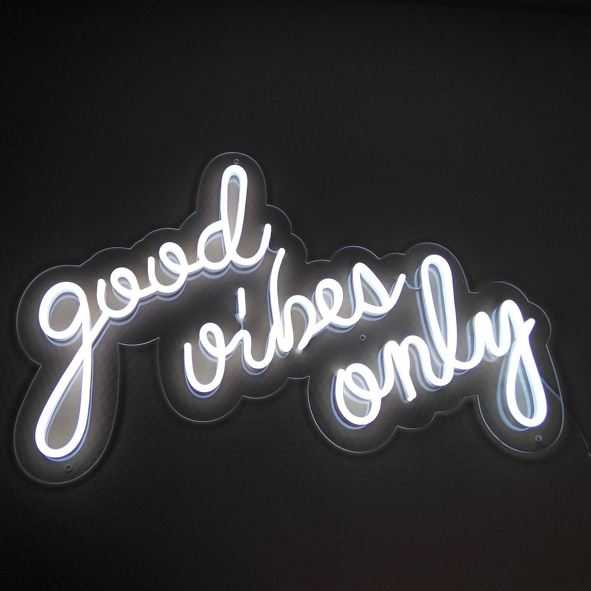 Good Vibes Only script LED neon sign glowing white against a dark wall