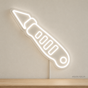 Watermarked concept mockup of Mini Craft Knife LED Neon Sign in White on a clear acrylic backboard.
