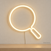 Watermarked concept mockup of Mini Magnifying Glass LED Neon Sign in Warm White on a clear acrylic backboard.