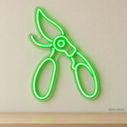 Watermarked concept mockup of Mini Pruning Shears LED Neon Sign in Green on a clear acrylic backboard.