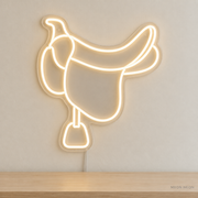Watermarked concept mockup of Mini Saddle LED Neon Sign in Warm White on a clear acrylic backboard.