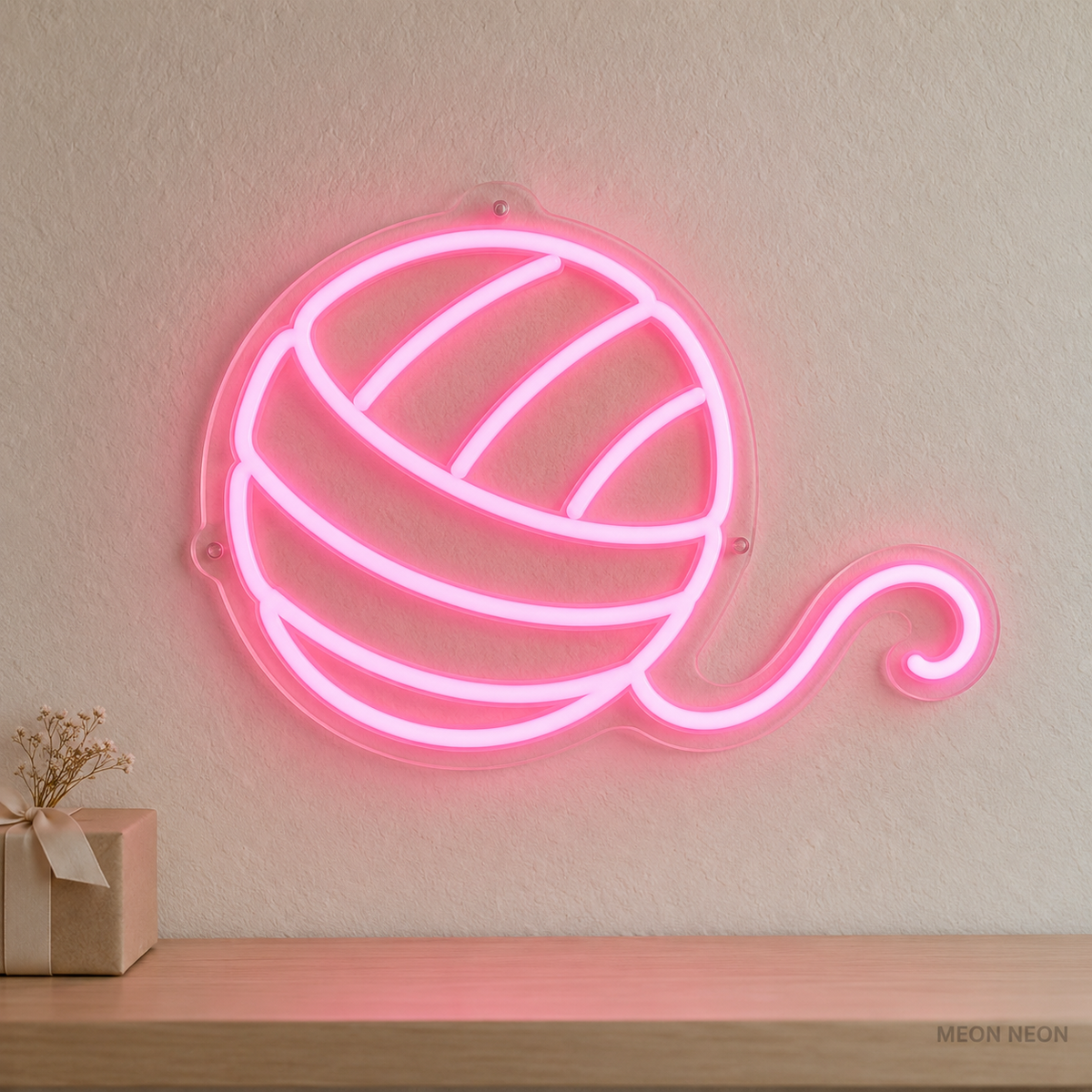 Watermarked concept mockup of the Mini Yarn Ball LED Neon Sign in Pink on a clear acrylic backboard.